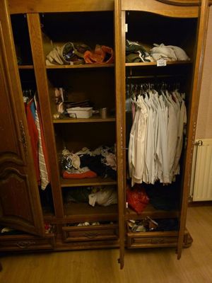 une armoire en bois sur laquelle sont posés des vêtements, dans une pièce