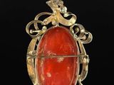 a gold and red stone pendant on a black background