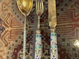 a glass table with silverware and a gold spoon and fork