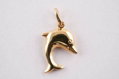 un gros plan d'un pendentif en forme de dauphin doré sur fond blanc