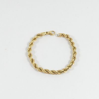 un gros plan d'un bracelet en cordon doré posé sur une surface blanche