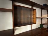 a wooden shelf with a glass door in the corner of a room