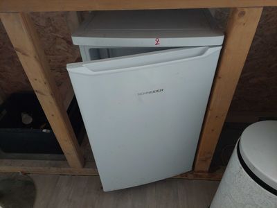 a small white refrigerator in the corner of a room