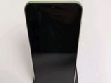 a black cell phone sitting on a stand on a white surface