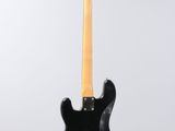 a black electric guitar hanging from a string on a white background