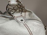 a white purse with a metal handle on a table