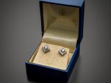 une photo d'une paire de boucles d'oreilles en diamant dans un écrin bleu