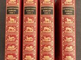 trois livres rouges ornés d'illustrations dorées, posés sur une table