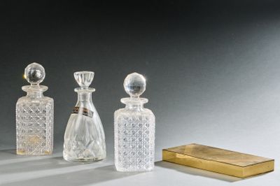 trois bouteilles en verre et une boîte dorée posées sur une table