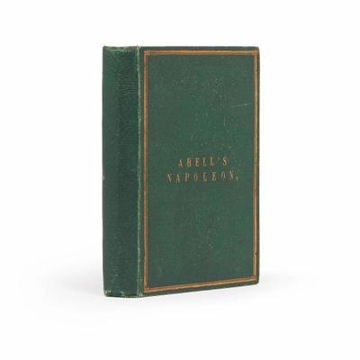 un livre vert orné de lettres dorées, posé sur une surface blanche