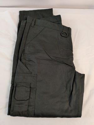 un pantalon cargo vert foncé posé sur un drap blanc sur un lit