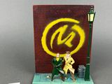 a figurine of a man sitting on a bench in front of a sign