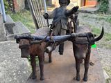 a statue of a man sitting on a cart with two oxen