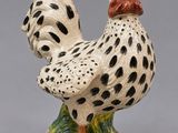 une figurine en céramique représentant un coq posé sur un rocher
