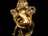 a gold figurine of a woman sitting on a chair