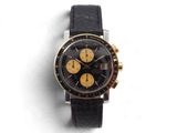l'image d'une montre noire et or sur une surface blanche