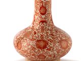 un vase rouge et blanc posé sur une surface blanche