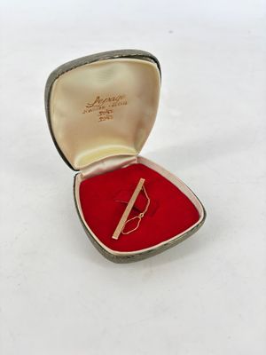 une image représentant une petite boîte rouge contenant une pince à cravate argentée