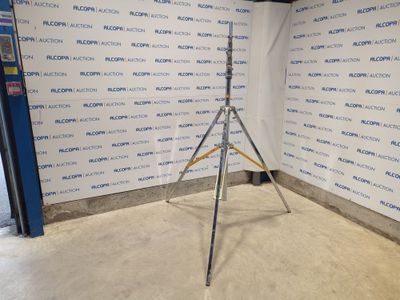 On voit l'image d'un trépied posé devant un mur sur lequel est accrochée une pancarte.