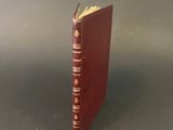 a red book with gold trim sitting on top of a table