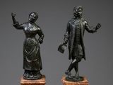 deux statues en bronze représentant un homme et une femme, posées sur des socles en marbre