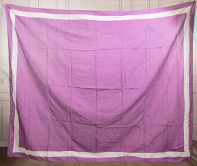 purple and white quilt hanging on a clothes line in a room