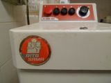 une machine à laver blanche munie d'un bouton rouge, dans une salle de bains