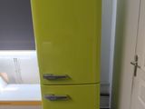 lime green refrigerator in the corner of a room with a white bathtub in the background