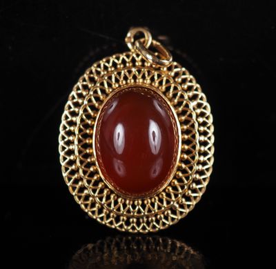 a gold and carneline pendant on a black background