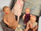 a group of dolls sitting inside of an open suitcase