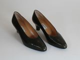 une paire d'escarpins en cuir noir à bout pointu posés sur une surface blanche