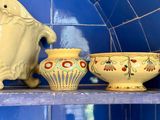 a shelf with a blue tiled wall and a shelf with yellow ceramic bowls and vases on it