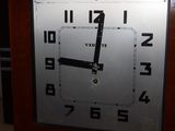 a clock that is sitting on the floor in front of a wall