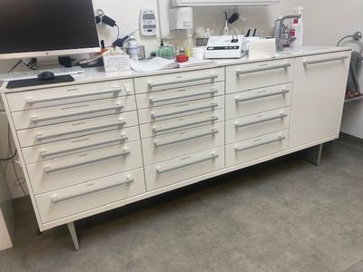 une armoire blanche avec des tiroirs, sur laquelle est posé un ordinateur