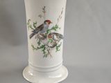 un vase blanc orné d'un oiseau, posé sur une table