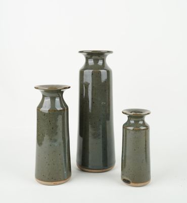 three green vases sitting next to each other on a white surface