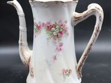 a white tea pot with pink flowers on it