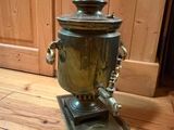 a metal coffee urn sitting on a wooden floor