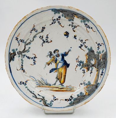 une assiette bleue et blanche sur laquelle sont représentés une femme et un oiseau