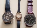 three different watches are lined up on a white surface