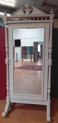 un miroir posé sur un pied dans une pièce aux murs rouges