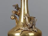 un vase en or orné d'un oiseau, posé sur une table