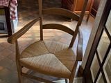 a wooden chair sitting in a kitchen next to a table with a checkered tablecloth on it