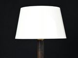 une lampe de table en laiton avec un abat-jour blanc sur fond noir