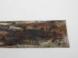 a close up of a piece of rusted metal on a white surface