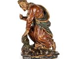 une image représentant une statue d'un homme à genoux, tenant un oiseau dans la main