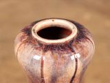 a brown vase sitting on top of a wooden table