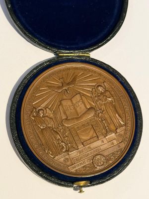 une médaille d'or dans un écrin bleu posé sur une surface blanche