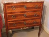 a small chest of drawers next to a chair in a room