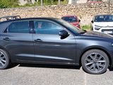 the car is parked in the parking lot next to a stone wall